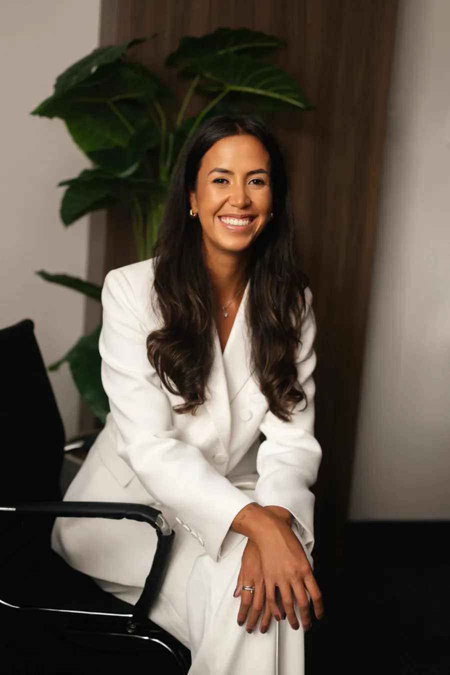 Dra. Carolina Winheski sentada em seu escritório, com blazer branco